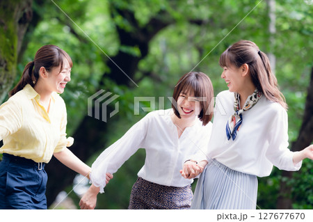 新緑の下を並んで歩く女性グループ 127677670