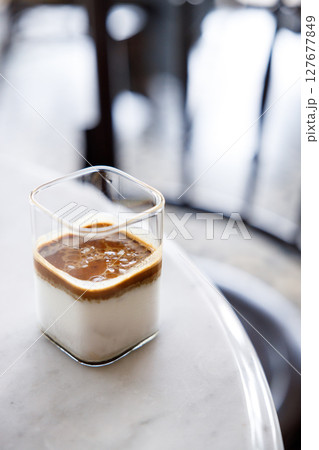 Cup of milk dirty coffee on white marble table by the window. 127677849