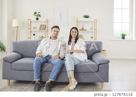 Portrait of young happy married couple sitting on sofa in the living room at home together. Portrait of young happy married couple sitting on sofa in the living room at home together. 127678118