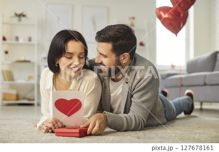 Happy Couple Unwrapping Gift With Red Heart For Valentine's Day At Home 127678161