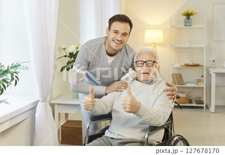 Positive health care worker embraces old male patient in wheelchair  127678170