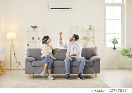 Married Couple Turning On Air Conditioner To Control Climate At Home 127678184