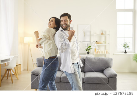 Smiling couple dancing together in cozy living room, celebrating and sharing happy moments together. Smiling couple dancing together in cozy living room, celebrating and sharing happy moments together. 127678189