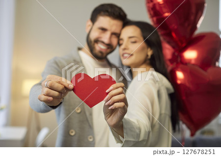 Young couple holding heart in hands and hugging celebrating holiday. Valentines day concept. Young couple holding heart in hands and hugging celebrating holiday. Valentines day concept. 127678251