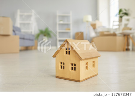 Wooden House Figurine On Floor Of New Home During Relocation Wooden House Figurine On Floor Of New Home During Relocation 127678347