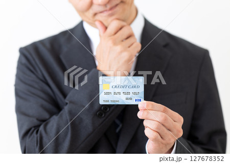 クレジットカードを持って悩むスーツ姿のビジネスマン男性 127678352