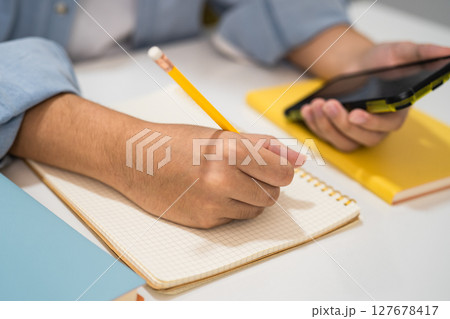 Teenage write in notebook and use mobile phone search data online to online learning university education. Teenage write in notebook and use mobile phone search data online to online learning university education. 127678417