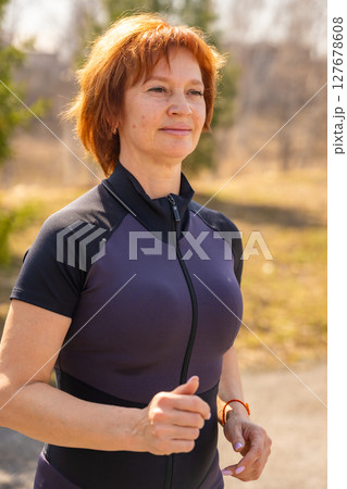 Woman running in a park as part of her morning fitness routine. Cardio activity, healthy lifestyle, and self-discipline outdoors. 127678608