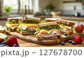 Freshly made sandwich with lettuce, cheese and bread surrounded by drinks 127678700