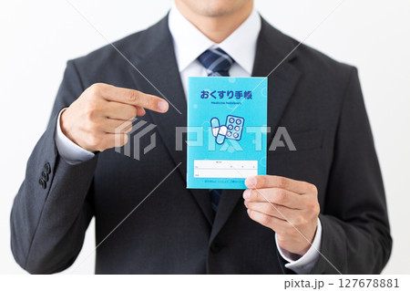 お薬手帳を持つスーツを着たミドル男性ビジネスマン 127678881