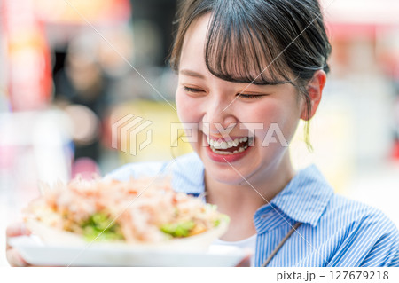 屋外でたこ焼きを食べる女性｜大阪府大阪市道頓堀にて 127679218