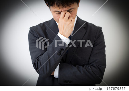 目頭を押さえて悩むスーツを着たミドル男性ビジネスマン 目頭を押さえて悩むスーツを着たミドル男性ビジネスマン 127679855