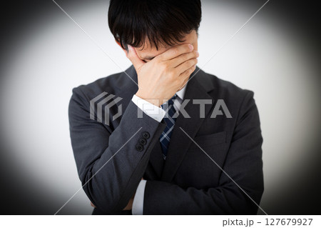 顔を覆って悩むスーツを着たミドル男性ビジネスマン 顔を覆って悩むスーツを着たミドル男性ビジネスマン 127679927