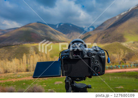Camera on tripod capturing serene mountain landscape 127680109