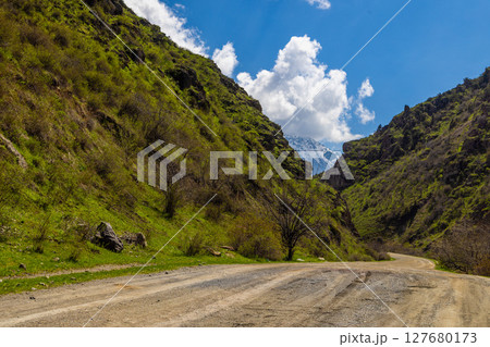 Serene road winding through peaceful mountainous landscape 127680173