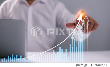 Businessman pointing at upward graph with glowing arrows, representing financial growth, success strategy, business progress, increasing revenue, investment returns, and future market opportunities. 127680434