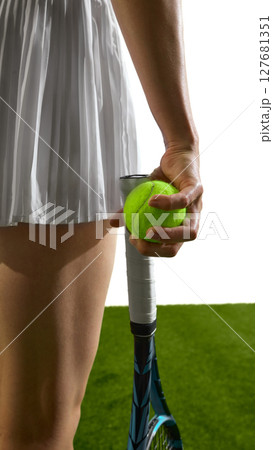 Tennis player holding ball and racket on grass court background Tennis player holding ball and racket on grass court background 127681351