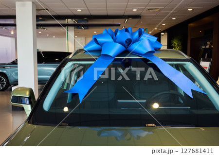 The new car is wrapped in a red bow. Beautiful gift concept. The new car is wrapped in a red bow. Beautiful gift concept. 127681411