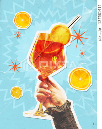 Hand holding vibrant cocktail collage with citrus and abstract blue background elements 127681412