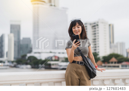 Happy young southeast asian woman and teenager blogger using smartphone for searching tourism guide. World travel explorer concept local cultural experience in Bangkok Asia on Chao Phraya river 127681483