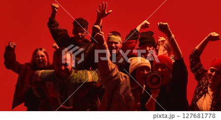 Protesters raising fists and shouting in solidarity for human rights under dramatic red lighting. 127681778