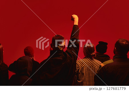 Protesters stand united against red backdrop symbolizing global economic strife and human rights 127681779