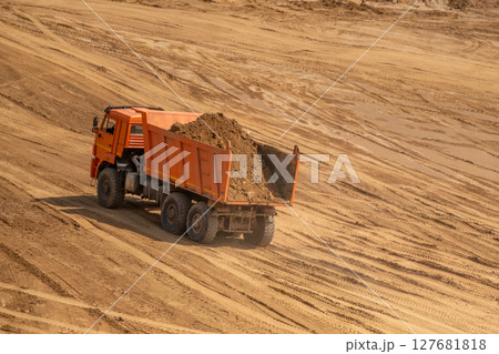 A loaded car drives out of a sand quarry. Sunny weather and clear skies 127681818