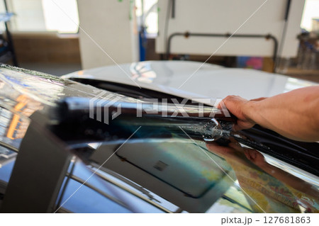 The Professional Windshield Tinting Process Conducted in a Modern Auto Showroom Environment 127681863