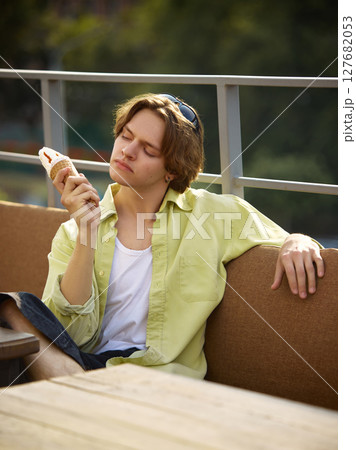 Chill style. Young man relaxing on outdoor patio with ice cream cone Chill style. Young man relaxing on outdoor patio with ice cream cone 127682053