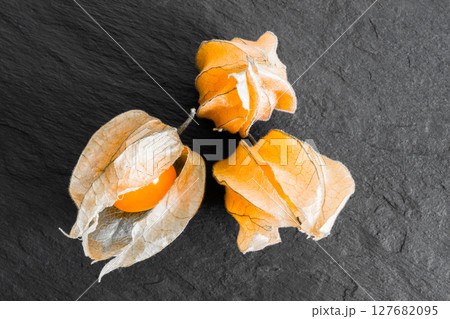 Cape Gooseberries on Black Rock Surface Background 127682095