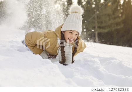 Happy winter fun, excited girl snow sledging in wintertime, playing during woodland nature adventure Happy winter fun, excited girl snow sledging in wintertime, playing during woodland nature adventure 127682588