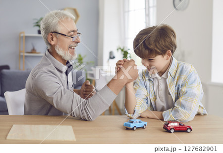 Happy grandfather and grandson family funny arm wrestling, having fight showing family male power Happy grandfather and grandson family funny arm wrestling, having fight showing family male power 127682901