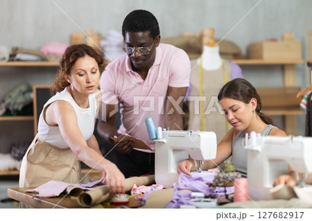 Two students working with textile and others sewing Two students working with textile and others sewing 127682917