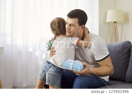 Loving daughter giving her father gift for Father Day, happy family celebrating special occasion. 127682998