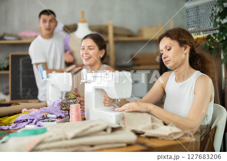 Adult woman stitching at machine during sewing class for adults 127683206
