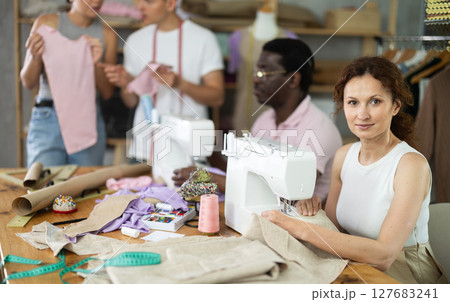 Adult woman stitching at machine during sewing class for adults Adult woman stitching at machine during sewing class for adults 127683241
