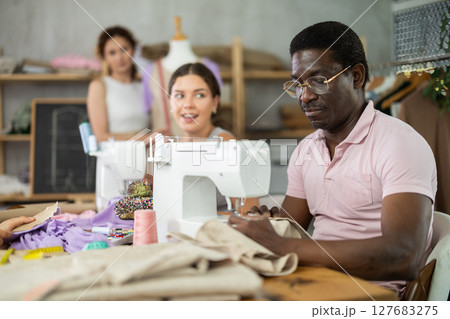 Young girl talking and sewing, other working with mannequin Young girl talking and sewing, other working with mannequin 127683275