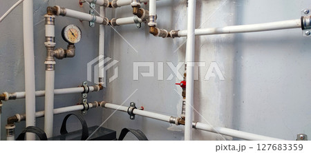 Efficient home plumbing concept: interior water pressure system with PVC piping, metal fittings, and pressure gauge. Efficient home plumbing concept: interior water pressure system with PVC piping, metal fittings, and pressure gauge. 127683359