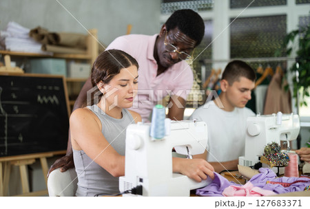 Young woman stitching at machine during sewing class for adults 127683371