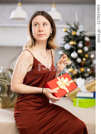 Concentrated woman wants to open a Christmas present Concentrated woman wants to open a Christmas present 127683403