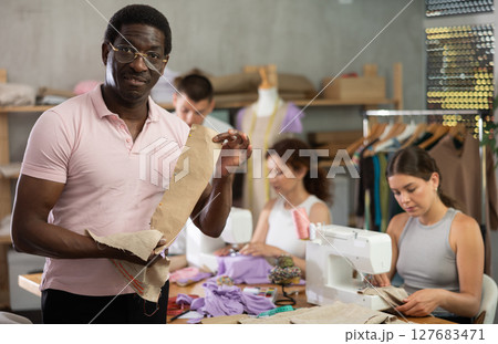 Positive middle-aged man holding textile detail fixed on paper Positive middle-aged man holding textile detail fixed on paper 127683471