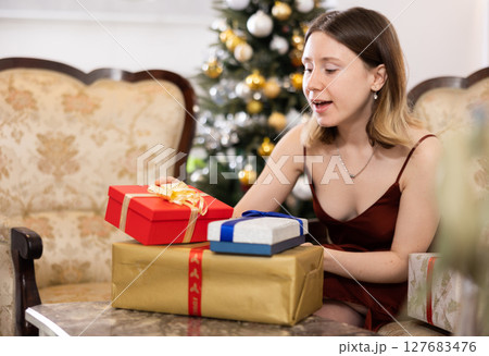 Happy young woman prepares Christmas presents Happy young woman prepares Christmas presents 127683476