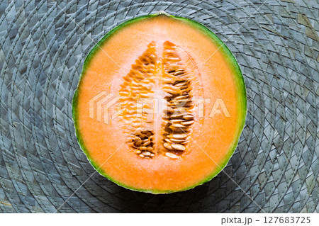 Half of Hami Melon Fruit on Green Straw Mat Background Surface Half of Hami Melon Fruit on Green Straw Mat Background Surface 127683725