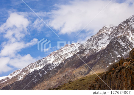 Majestic snow-covered mountains in serene daytime setting 127684007