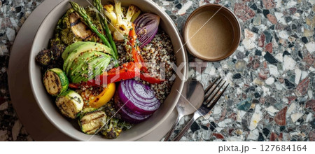 Colorful Salad Bowl with Quinoa, Avocado, Grilled Veggies, and Tahini on Terrazzo 127684164