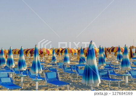 Parasols and sunbeds in Rimini resort beach Parasols and sunbeds in Rimini resort beach 127684169