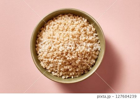 Ceramic Bowl of Cooked Brown Rice on Pastel Beige Background 127684239