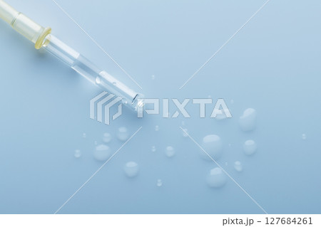 Pipette with transparent liquid on glossy background 127684261