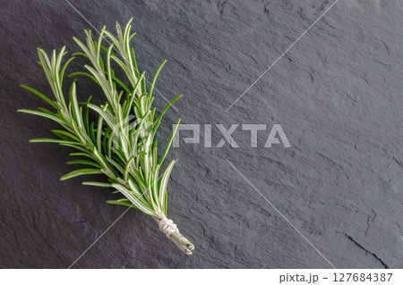 Rosemary Bundle on Black Stone Surface Background 127684387