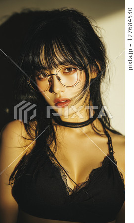 Confident young woman poses with stylish glasses and casual outfit in warm lighting setting 127684530
